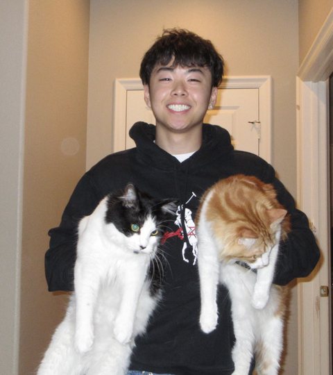 Shawn Liu holding Coconut, a black-and-white cat, and Kumquat, an orange-and-white cat